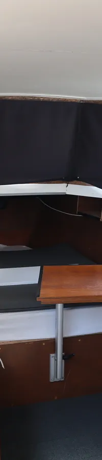 De kajuit van een boot met houten wanden, een tafel, kussens en ramen met zwarte gordijnen. — WSA vlet Ex patrouille boot