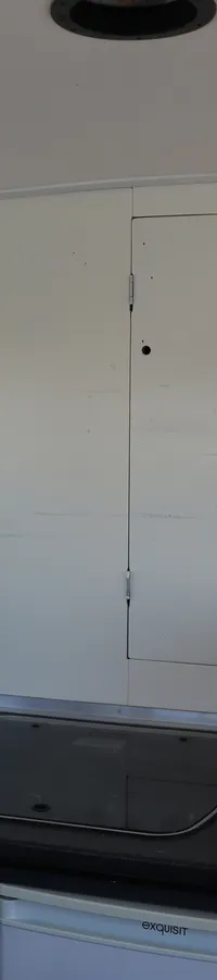 De foto toont een bootinterieur met een keukenblok, een raam, een witte kast en een doorgang naar buiten met een trapje.