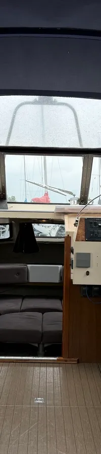 De foto toont het interieur van een boot met een donkerblauwe kap, twee stuurstoelen en een houten vloer. — Joda 7500