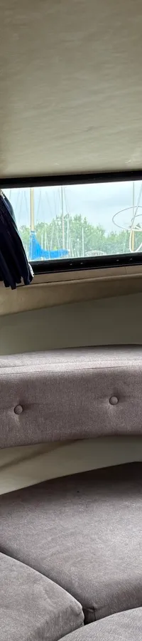De foto toont het interieur van een boot met een houten deur, grijze kussens en ramen met blauwe gordijnen. — Joda 7500