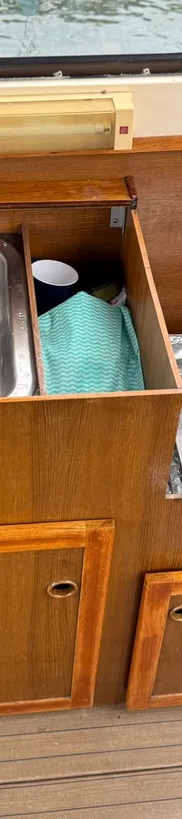 Een kombuis met een roestvrijstalen spoelbak en een tweepits gasfornuis, ingebouwd in houten kasten.