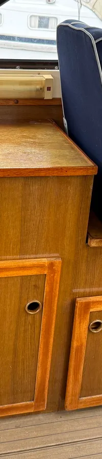 Een blauwe bootstoel met witte biezen en een houten kastje met twee deurtjes en een kookplaatje.