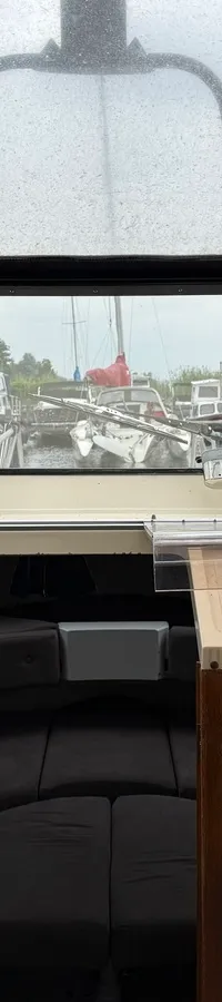 De foto toont het interieur van een boot met een stuurwiel, dashboard en uitzicht op een jachthaven. — Joda 7500