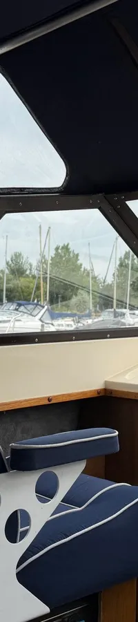 De foto toont het interieur van een boot met een blauw-witte stoel en uitzicht op een haven met andere boten. — Joda 7500