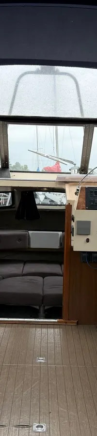 De foto toont het interieur van een boot met een donkerblauwe kap, twee stuurstoelen en een houten vloer. — Joda 7500