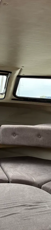 De foto toont het interieur van een boot met een U-vormige zithoek, ramen en nautische kussens. — Joda 7500