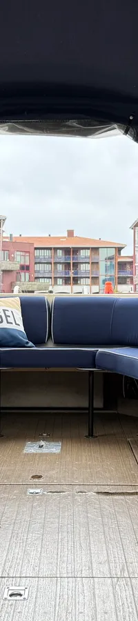 De foto toont het interieur van een boot met een blauwe bank, een kussen met "IJSVOGEL" erop, en houten panelen. — Joda 7500