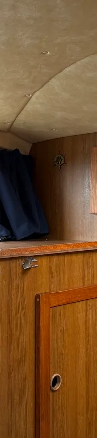 De foto toont het interieur van een kajuit met houten wanden, een gestoffeerd plafond en een gestreepte kussen. — Joda 7500