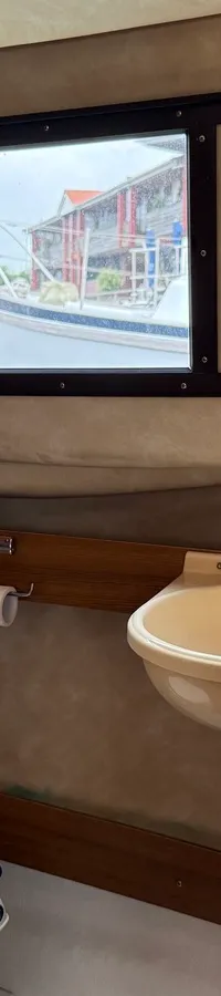 Een interieur van een boot met een toilet, wasbak, ramen met gordijnen en een zitbank. — Joda 7500