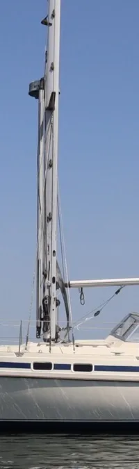 Een witte zeilboot met blauwe strepen op het water, met een buitenboordmotor en zonnepaneel aan de achterkant. — Contest 38S