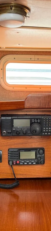 Een interieur van een boot met een Furuno display, diverse elektronica, een schakelpaneel, meters en een raam met rood…