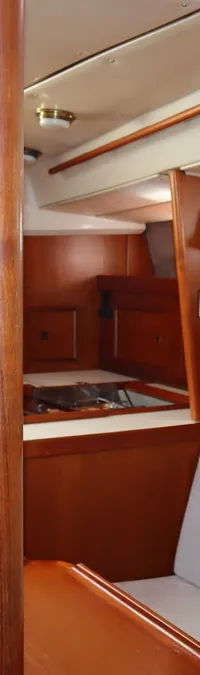 Een houten interieur van een boot met een kombuis, salonbank, tafel, trap en patrijspoorten is zichtbaar. — Contest 38S