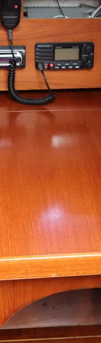 Een houten interieur met een navigatietafel, elektronica, twee rode opbergbakjes en een beklede zitbank.