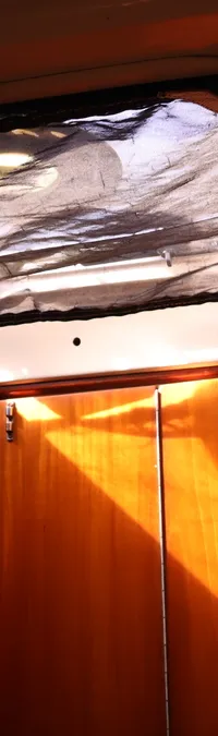 Een interieur van een boot met een open luik met een zwart net en houten kasten eronder. — Contest 38S