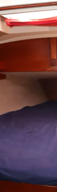 Een kajuit met een bed met een blauw laken, omringd door houten panelen en een open deur. — Contest 38S