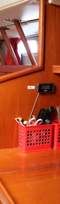 Een houten navigatiestation met een Furuno-scherm, marifoon, radio en twee rode opbergbakjes is zichtbaar.
