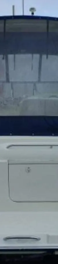 De achterkant van een witte boot met een blauwe cabriokap en transparante ramen is zichtbaar, liggend aan een steiger.
