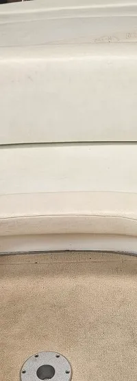 De foto toont een bootinterieur met beige gestoffeerde zitplaatsen en een beige vloerbedekking.