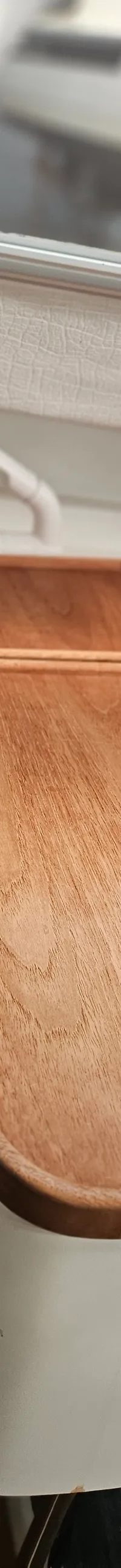 Een houten opklapbare tafel met een metalen handgreep aan de zijkant, gemonteerd op een witte console.