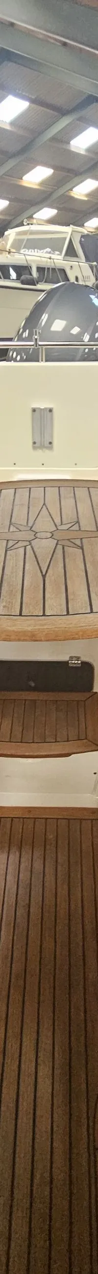 De foto toont het interieur van een boot met een houten tafel met kompasroos en een houten vloer. — Yamarin 68C