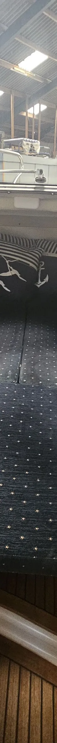De foto toont het interieur van een boot met donkerblauwe kussens met een stippenpatroon en twee kussens met zeemotieven.