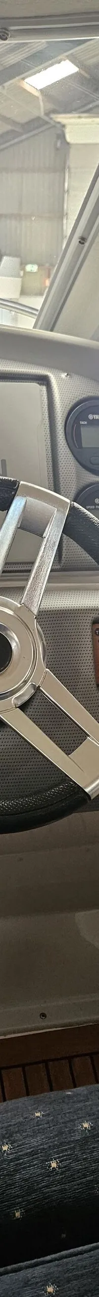 De foto toont het stuur van een boot met een Garmin-scherm, Yamaha-meters en een houten vloer. — Yamarin 68C