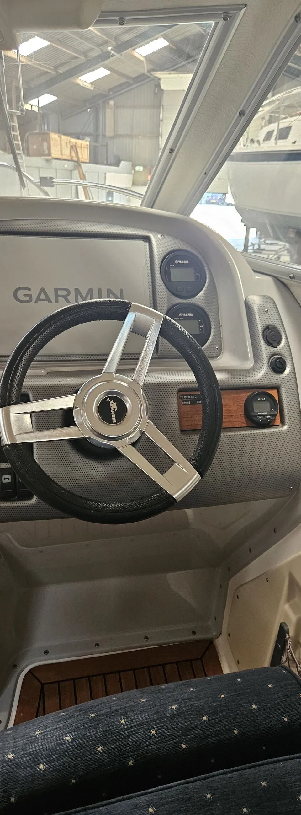 De foto toont het stuur van een boot met een Garmin-scherm, Yamaha-meters en een houten vloer. — Yamarin 68C