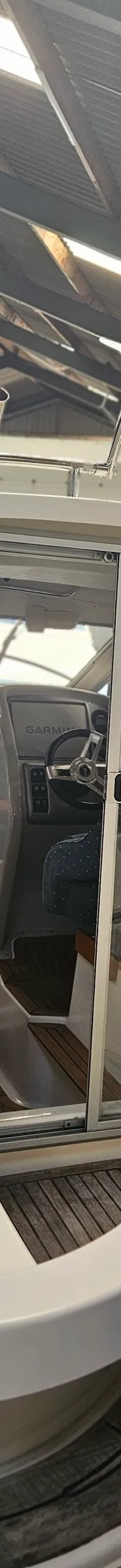 Een witte boot met een stuurhut en schuifdeur, gezien vanaf de achterkant, in een loods met een golfplaten dak. — Yamarin 68C