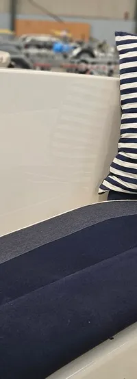 Een detailfoto van een bootinterieur met blauw-wit gestreepte kussens en een ankerpatroon, en blauwe zitkussens.