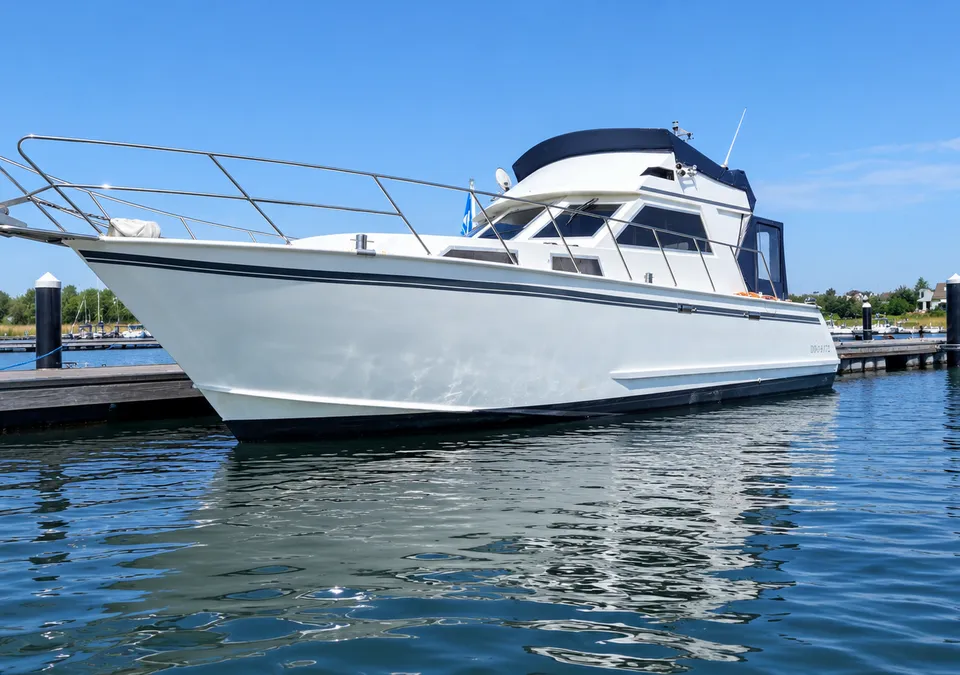 Een witte motorboot met een donkerblauwe kap ligt aangemeerd aan een houten steiger in een jachthaven. — Condor 105 Fly
