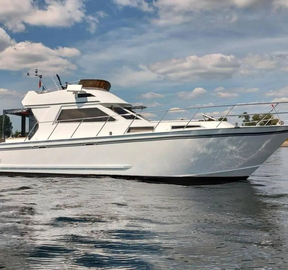 Een witte motorboot met de registratie "DUR-TC72" drijft op kalm water onder een bewolkte hemel. — Condor 105 Fly
