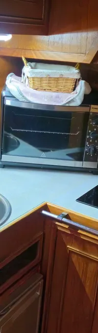 Een kombuis met een aanrecht, spoelbak, kookplaat, oven, en houten kasten en wanden.