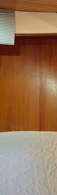 Een kajuit met een bed, een wastafel met kraan en een kastje, alles afgewerkt met hout. — Condor 105 Fly