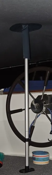 Een stuurwiel met een Shipmate-apparaat is zichtbaar in een boot, met een bezem en opgevouwen stoelen op de vloer.