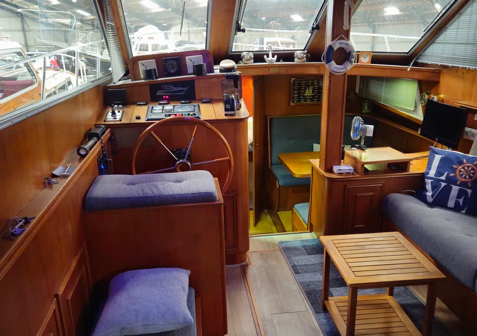 Het interieur van een boot met een stuurwiel, banken, een tafel en een kleine televisie. — Condor 105 Fly