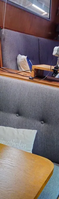 Een interieur van een boot met houten wanden, een grijze bank, een tafel en een ventilator. — Condor 105 Fly