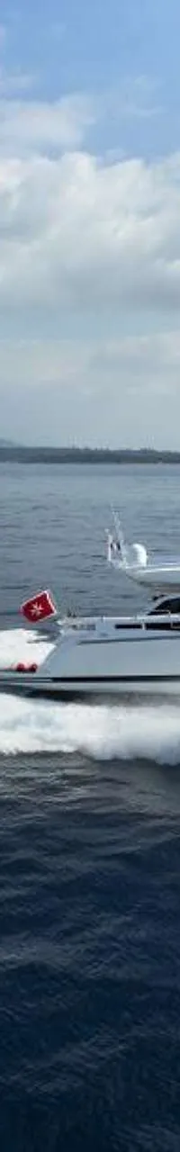 Een witte motorboot met blauwe accenten vaart snel over het water, met een grote schuimkraag achter zich. — Baia 100