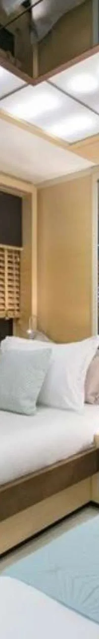 Een slaapkamer met twee eenpersoonsbedden, houten jaloezieën voor de ramen en een spiegelwand.