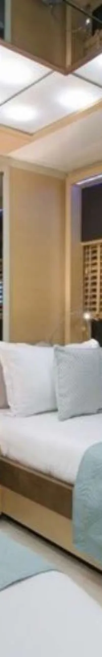 Een slaapkamer met twee eenpersoonsbedden, een nachtkastje met lamp en een spiegelwand.