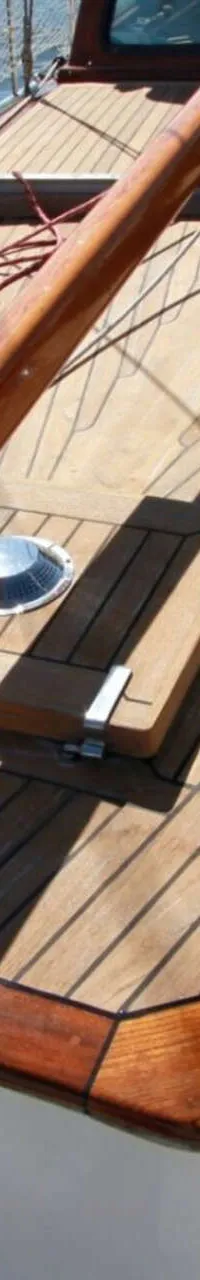 Een bovenaanzicht van het teakhouten dek van een boot met een houten mast en een lier. — Volkerak 46
