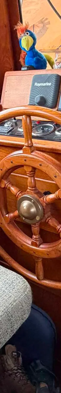 Een houten stuurwiel en diverse Raymarine-instrumenten zijn zichtbaar in de stuurhut van een boot. — Volkerak 46