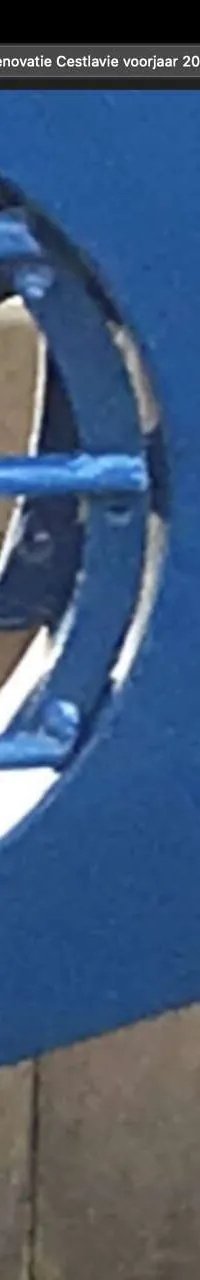 Een blauwe boegschroef met drie bladen is zichtbaar, omringd door een metalen rooster.