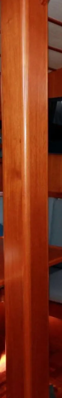 Een houten interieur met een zithoek, tafel, boekenplank, televisie en een kombuisgedeelte.