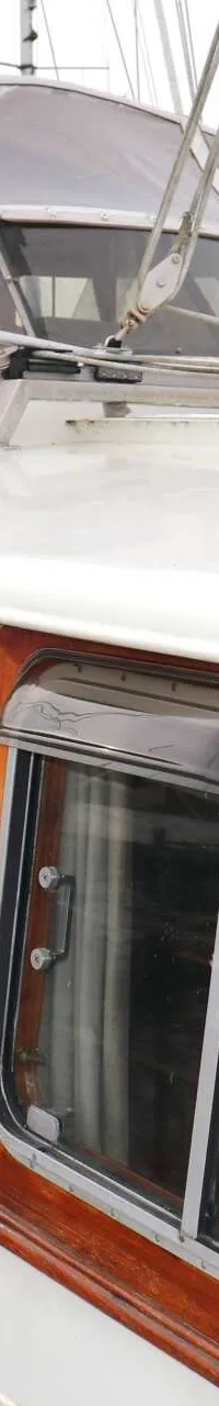 Een witte boot met houten accenten en ramen, met de naam "CECILIA" op de zijkant, ligt in het water. — Bloemsma Kotter 10.50