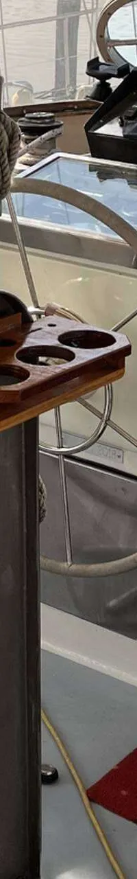 Een interieur van een boot met een stuurwiel, houten deuren en een rode mat op de vloer. — Bloemsma Kotter 10.50