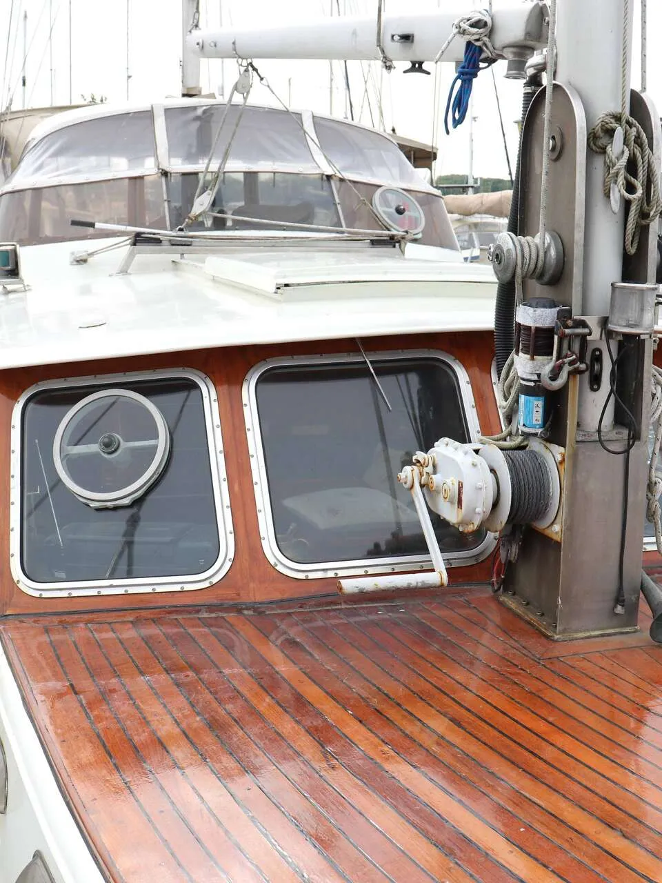 Een boot met een houten dek, voorruiten en een lier op het voordek ligt in een haven. — Bloemsma Kotter 10.50