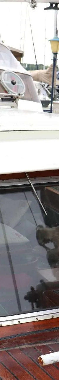 Een boot met een houten dek en kajuit, voorzien van een grote witte lier en een mast met touwen. — Bloemsma Kotter 10.50