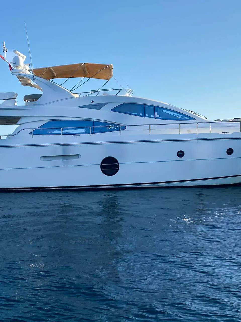 Een witte motorjacht met een bruine bimini-top en de tekst "DE VALK YACHT BROKERS" in de rechterbovenhoek. — Aicon 64