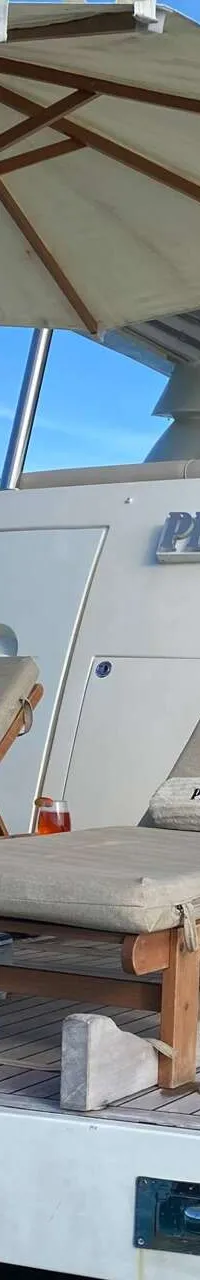 De achterkant van een wit jacht met de naam "PHILIP VICTOR II" is te zien, met twee ligstoelen en een parasol op het dek.