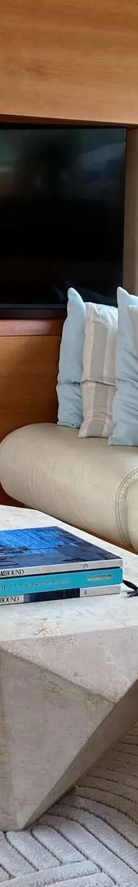 Een interieur van een boot met een bank, salontafel, televisie en uitzicht naar buiten. — Aicon 64